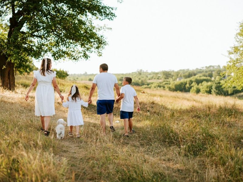 A family walking through a field with a dog